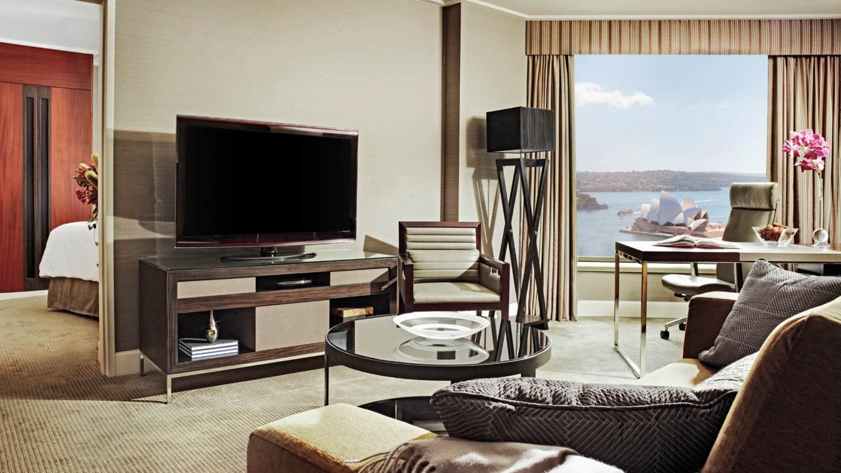 Four Seasons Hotel Sydney Esterno foto The photo shows a modern hotel room with a spacious and elegant design. It features a large flat-screen television situated on a wooden console. There’s a comfortable armchair next to the TV, and a round glass coffee table is positioned in front of a