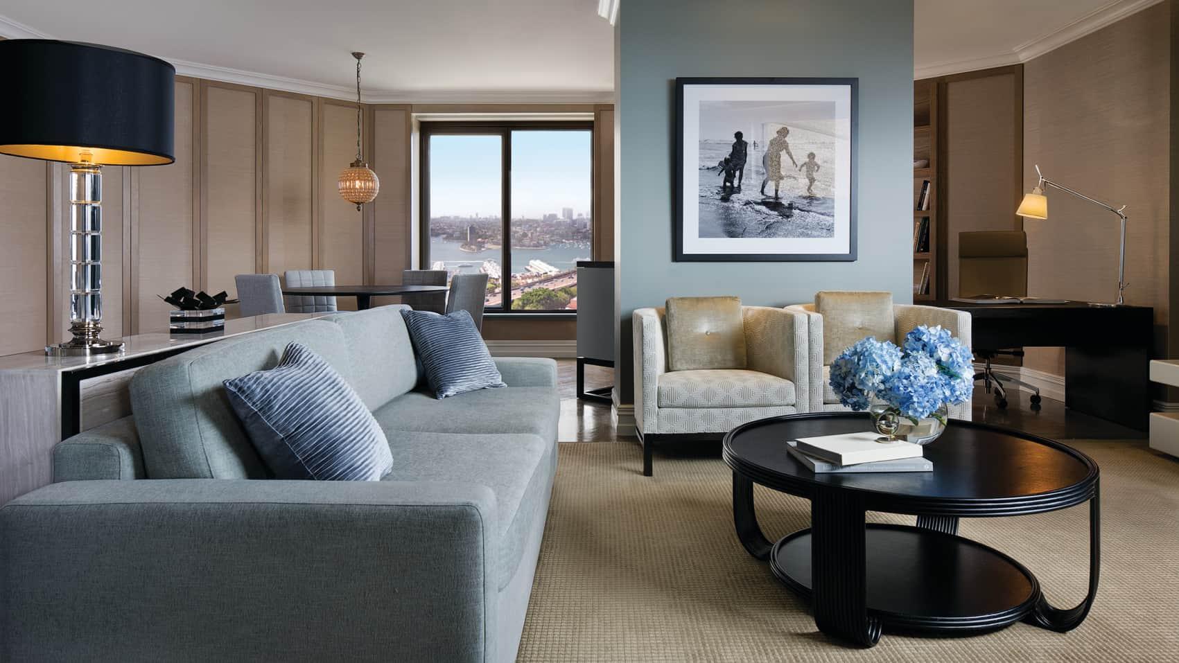 Four Seasons Hotel Sydney Esterno foto The photo depicts a modern and stylish living room area. It features a gray sofa with decorative cushions arranged neatly on it. In front of the sofa, there is a round coffee table, which has a vase of blue flowers as a centerpiece. To the side, ther