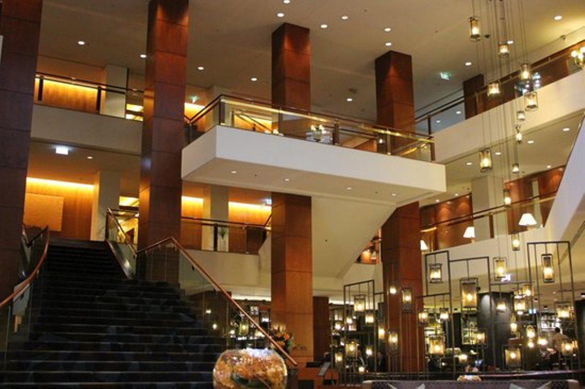 Four Seasons Hotel Sydney Esterno foto The photo shows the interior of a modern hotel lobby. It features a spacious and elegantly designed area with high ceilings, large windows, and a combination of warm lighting and wooden accents. There is a staircase leading to an upper level, creatin