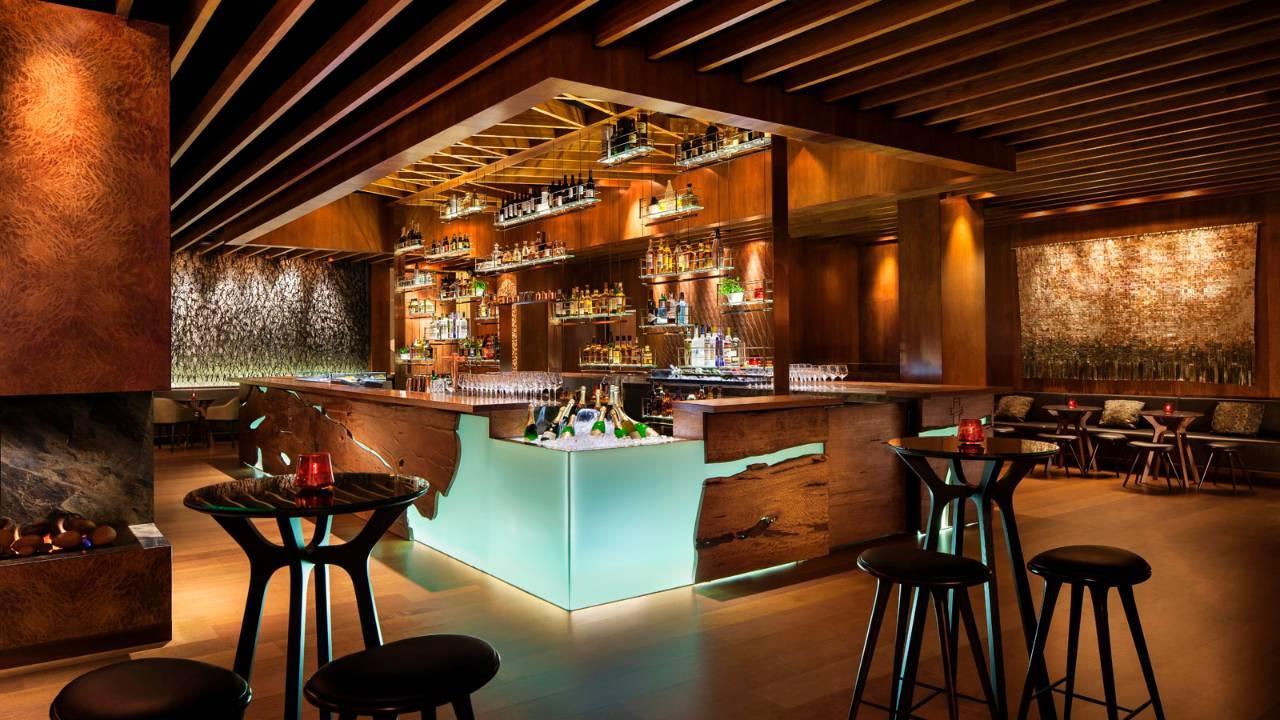 Four Seasons Hotel Sydney Esterno foto The image showcases a stylish, contemporary bar interior. The bar itself features a sleek design with a wooden structure and illuminated sections, creating a warm ambiance. Behind the bar, shelves are filled with a variety of bottles, indicating a we