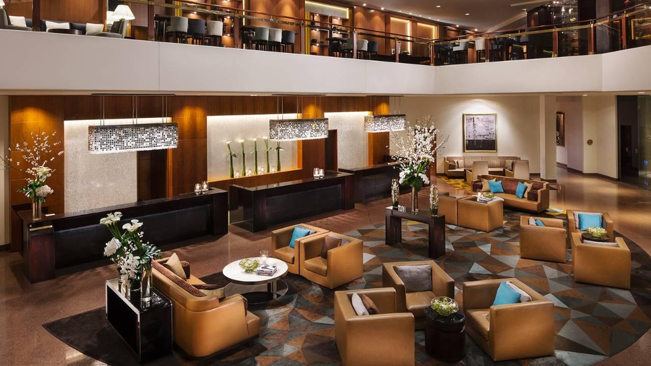Four Seasons Hotel Sydney Esterno foto The photo shows a stylish hotel lobby with a modern design. There is a spacious seating area featuring comfortable brown armchairs and a few accent pillows in vibrant colors. A circular coffee table is situated at the center of the seating area, surr